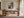 Light wood-framed autumn trees print displayed above a wooden desk in a sunlit office.