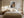 Light wood-framed autumn woodland print centered above a bed with cream bedding.