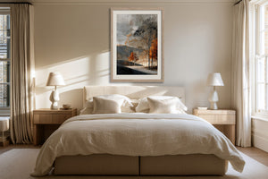 Light wood-framed autumn woodland print centered above a bed with cream bedding.