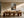Light wood-framed autumn trees print hanging above a long wooden dining table.