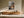 Light wood-framed autumn woodland print above a low wooden sideboard with ceramic objects.
