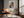 Light wood-framed autumn trees print above a leather lounge chair beside tall windows.
