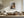 Light wood-framed autumn woodland print above a cream sectional sofa and low coffee table.
