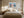 Light wood-framed mountain lake artwork centered above a bed with cream linens.