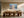 Light wood-framed mountain lake artwork above a long wooden dining table.