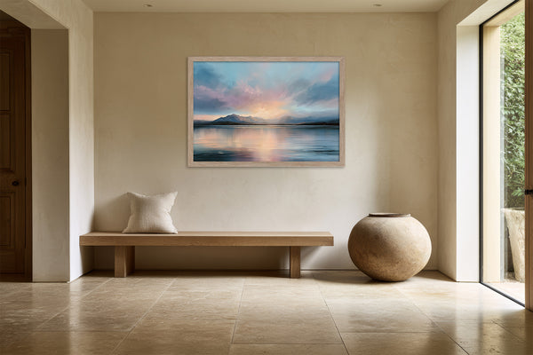 Light wood-framed mountain lake artwork above a bench beside a large ceramic vessel.