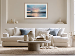 Light wood-framed mountain lake artwork above a cream sofa with blue accent pillows.