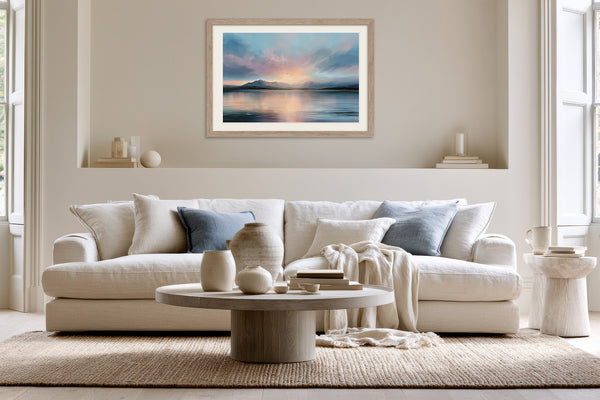 Light wood-framed mountain lake artwork above a cream sofa with blue accent pillows.