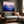 Violet Ranges mountain artwork in a slim wood frame above a gray sofa by a window.