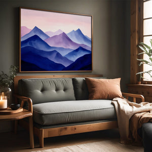 Violet Ranges mountain artwork in a slim wood frame above a gray sofa by a window.