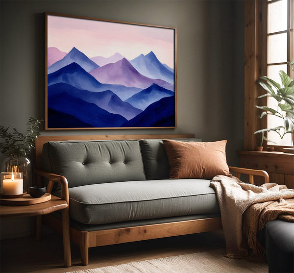 Violet Ranges mountain artwork in a slim wood frame above a gray sofa by a window.