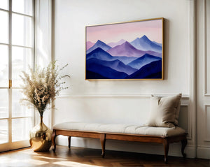 Violet Ranges mountain artwork in a gold-toned frame above a wooden bench and vase.