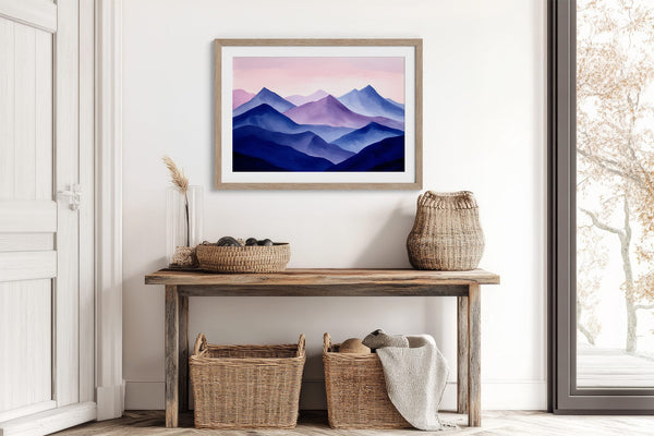 Violet Ranges mountain print in a light wood frame above a rustic console table with woven baskets.