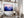 Violet Ranges mountain artwork in a dark frame displayed above a desk with shelves.