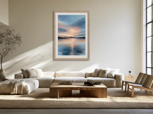 Light wood-framed mountain lake artwork above a cream sectional sofa in a sunlit living area.