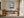 Light wood-framed mountain lake artwork displayed above a wooden desk beside tall glass doors.