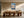 Light wood-framed mountain lake artwork above a long wooden dining table with sculptural chairs.
