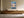 Light wood-framed mountain lake artwork hanging above a long wooden sideboard with ceramic vessels.