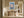 Light wood-framed mountain lake artwork above a rustic wooden bench in a sunlit hallway.