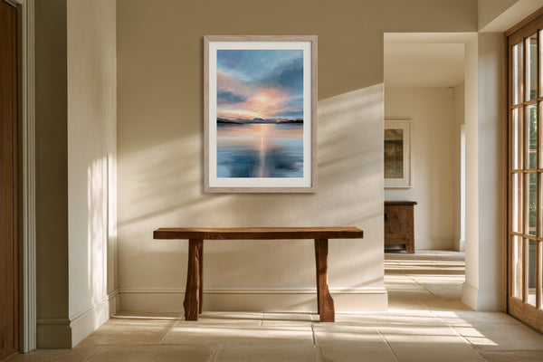 Light wood-framed mountain lake artwork above a rustic wooden bench in a sunlit hallway.