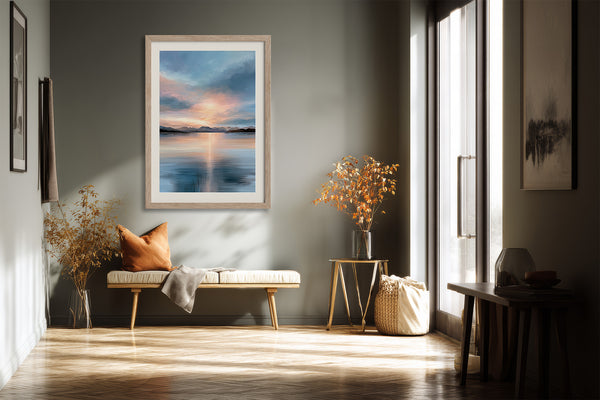 Light wood-framed mountain lake artwork above a small bench with an orange cushion in a hallway.