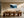 Framed winter forest artwork above a long wooden dining table with sculptural chairs.