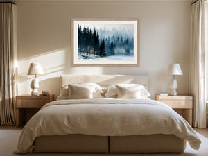 Framed snowy pine forest artwork centered above a bed with cream linens.