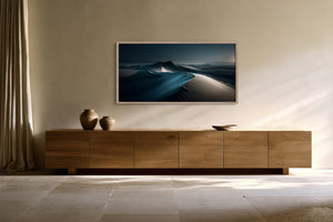 Light-framed dune artwork above a long wooden sideboard with ceramic vessels.