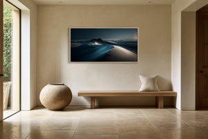 Light-framed dune artwork above a wooden bench with a large round ceramic vase.