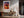Light wood-framed sunset tree print above a wooden console with vases and dried branches.
