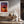 Light wood-framed sunset tree print above a wooden console with vases and dried branches.