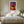 Light wood-framed sunset tree print centered above a neatly made bed.