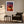 Light wood-framed sunset tree print above an armchair, side table, and floor lamp.