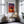 Thin gold-framed sunset tree print above a gold chair and glass side table.