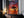 Large thin-framed sunset tree artwork leaning on a dark cabinet beside lit candles.