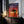 Large thin-framed sunset tree artwork leaning on a dark cabinet beside lit candles.