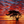 Silhouetted tree beside still water under a vivid red and orange sunset sky