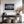 Light wood-framed mountain reflection print above a console table between two staircases.