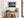 Light wood-framed mountain reflection print above a rustic console with woven baskets and pottery.