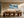Framed snowy mountain artwork displayed above a long wooden dining table with sculptural chairs.