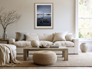 Light wood-framed mountain lake artwork above a cream sofa and wooden coffee table.