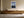 Light wood-framed mountain lake artwork above a low wooden sideboard with ceramic vessels.