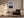 Light wood-framed mountain lake artwork above a dark armchair, side table, and floor lamp.