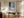 Light wood-framed snowy forest print above a wooden desk beside tall curtains.