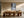 Light wood-framed winter forest path print above a long wooden dining table and chairs.