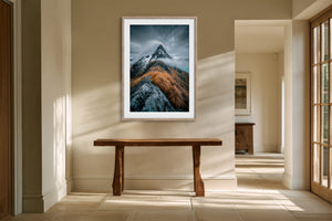 Framed mountain print above a wooden console table in a sunlit hallway.