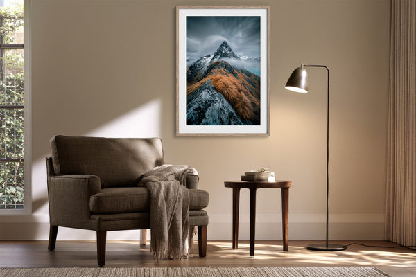 Framed mountain print above an armchair and side table with a floor lamp.