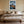 Framed mountain print centered above a bed with neutral bedding and bedside tables.