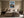 Framed mountain print above a bed with dark bedside tables and neutral bedding.