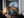 Large mountain artwork in a thin dark frame leaning on a wooden cabinet beside candles.